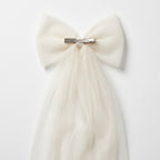 Feminine tulle bow clip on white background showcasing delicate design, hand-sewn Spanish tulle, alligator clip, and lightweight structure.