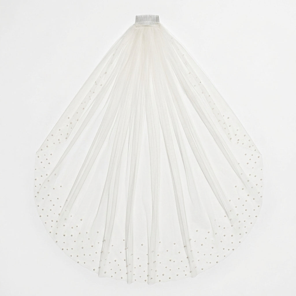 Flat-lay of light ivory KAI cathedral veil with pearl-embellished edges on white background