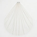 Flat-lay of light ivory KAI cathedral veil with pearl-embellished edges on white background