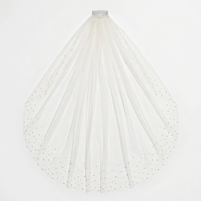 Flat-lay of light ivory KAI cathedral veil with pearl-embellished edges on white background
