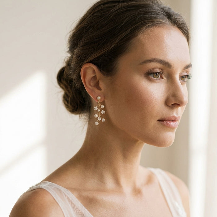 Close-up of delicate TALIA earrings on a bridal model with soft updo, ivory background, highlighting faux pearls and ivory beads.